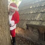 Santa peeping out from behind a tree